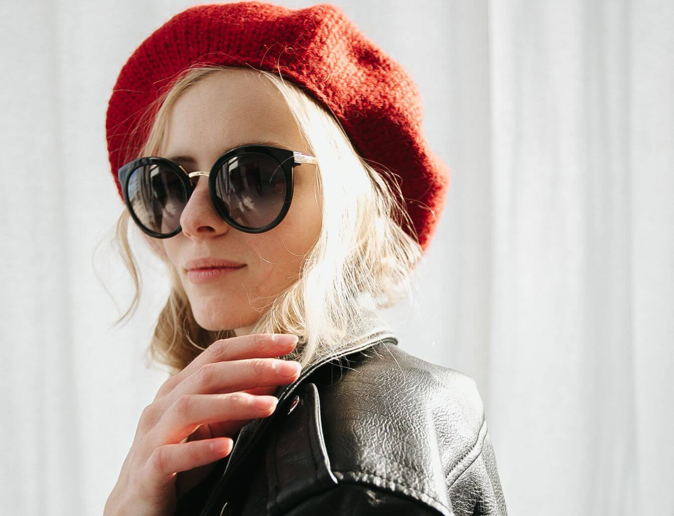 Person wearing a red beret and black sunglasses with a light gray background