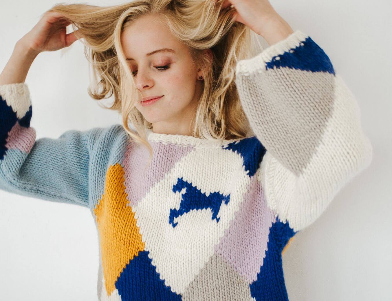 Woman wearing a colorful sweater with geometric patterns and a horse design.
